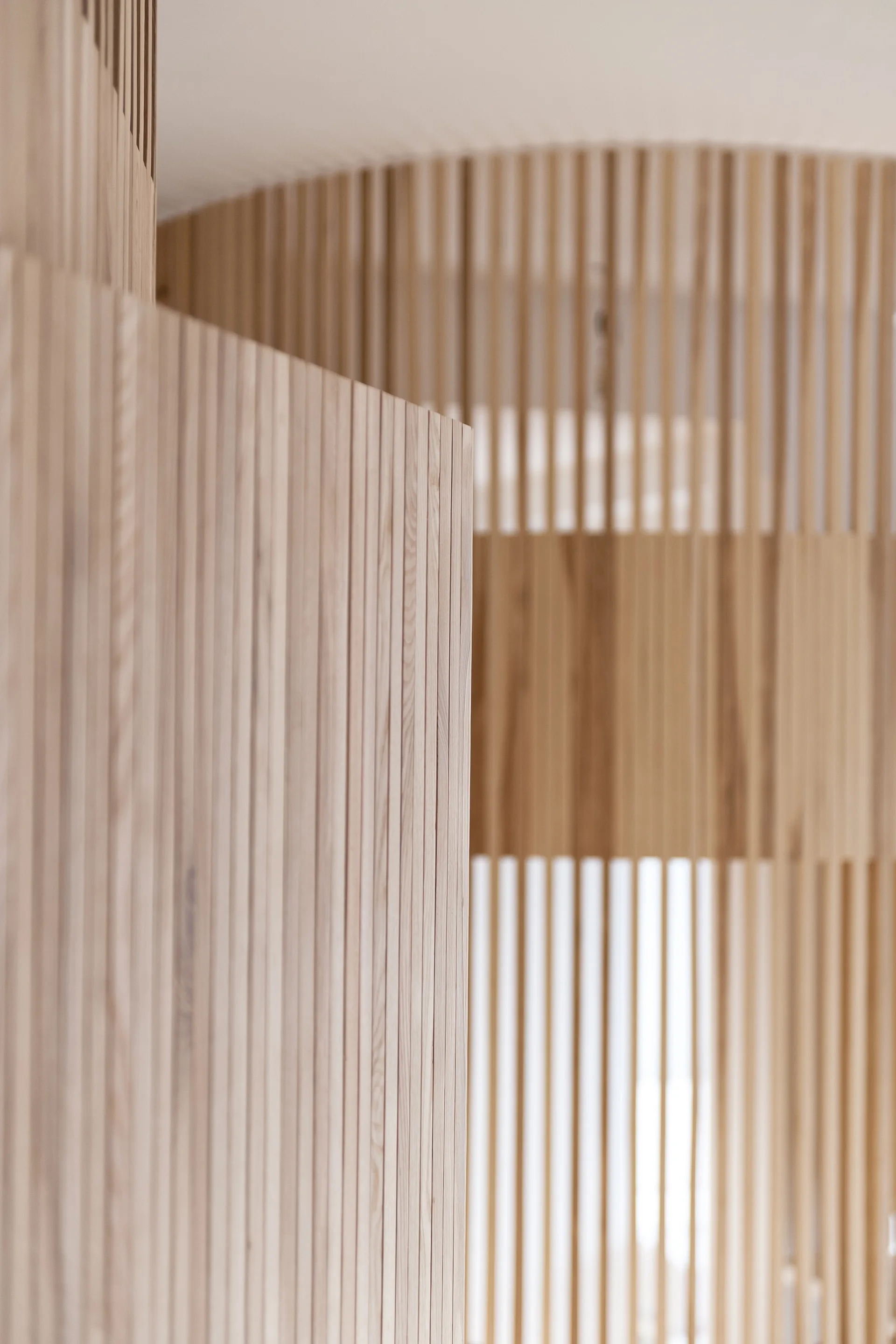 A close-up view of vertical light-toned wood slats arranged in a repeating linear pattern on an interior partition screen.