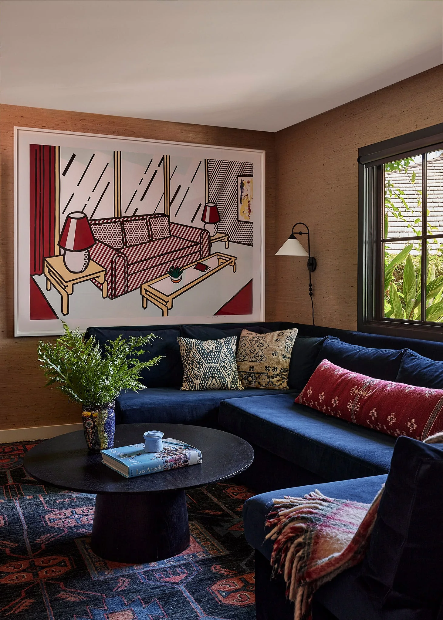 A navy sectional sofa sits against brown textured walls beneath a large framed graphic print in a cozy living room corner.