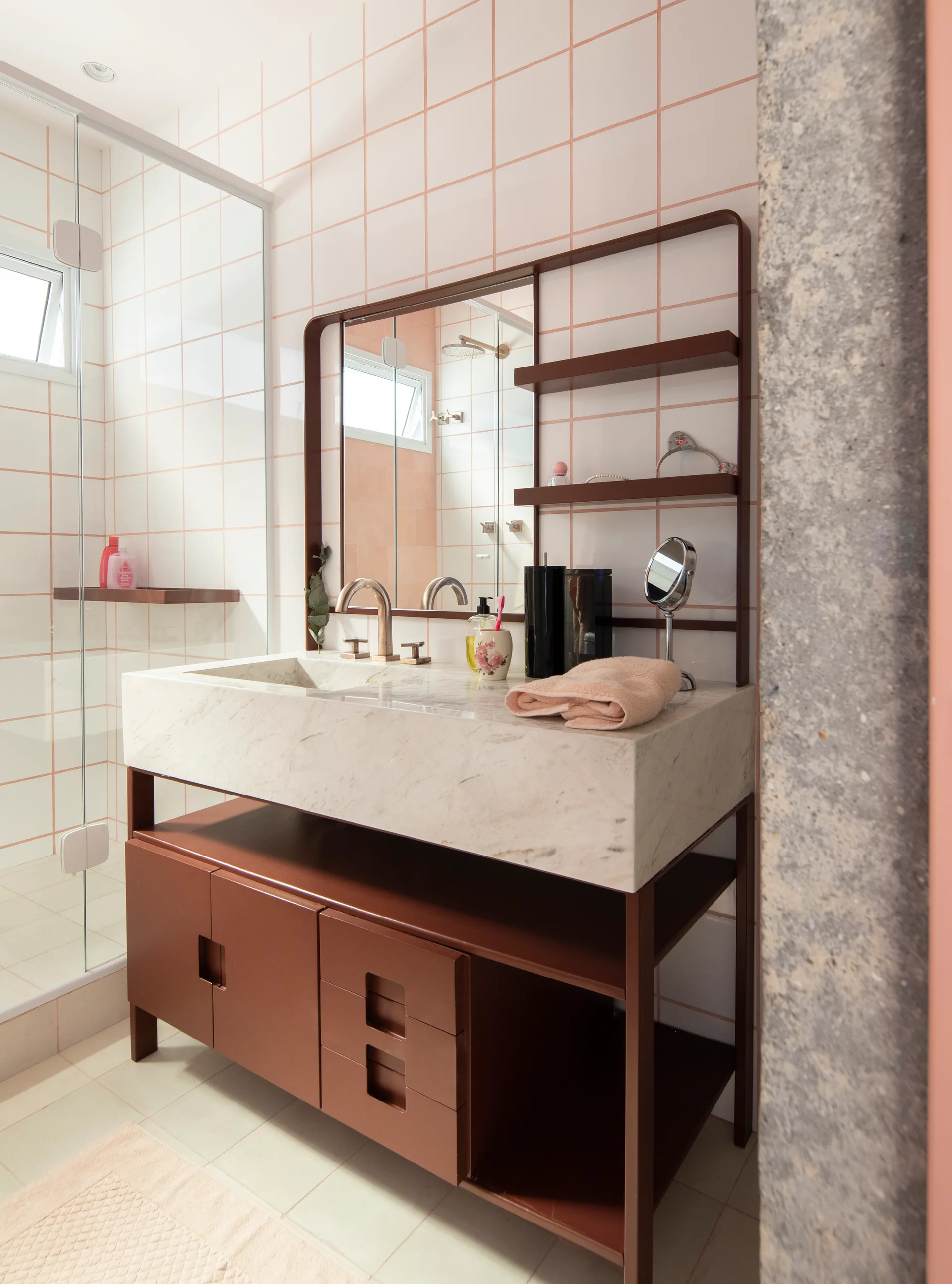 A modern bathroom features a marble block sink vanity with a brown frame against white wall tiles accented by pink grout.