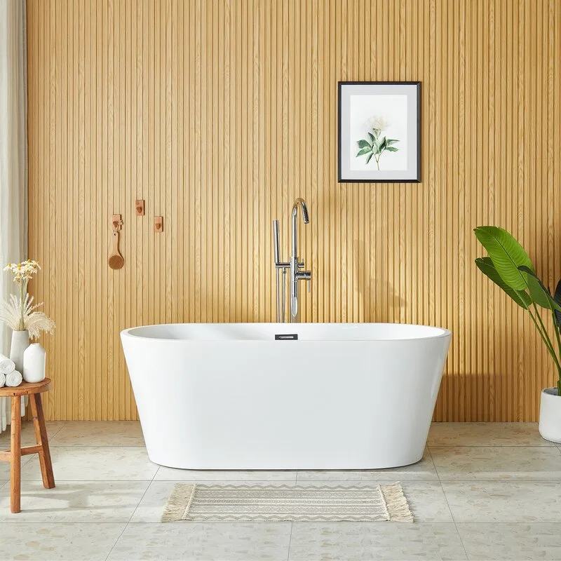 A white freestanding oval bathtub sits centered in front of a light wood slatted wall on speckled stone floor tiles.