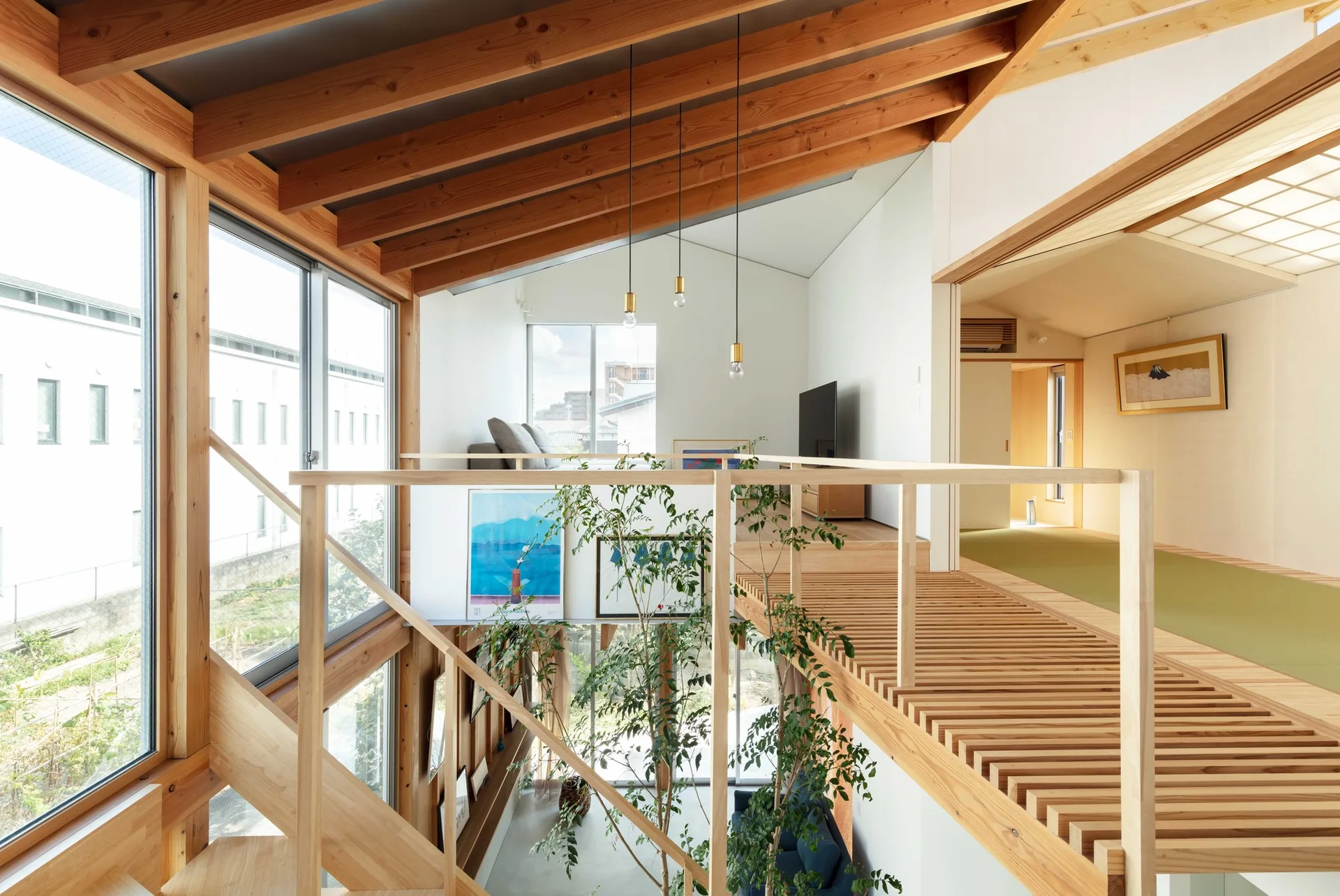 A modern double-height interior featuring a slatted wooden mezzanine walkway, exposed timber ceiling beams, large windows, and a tall indoor plant.