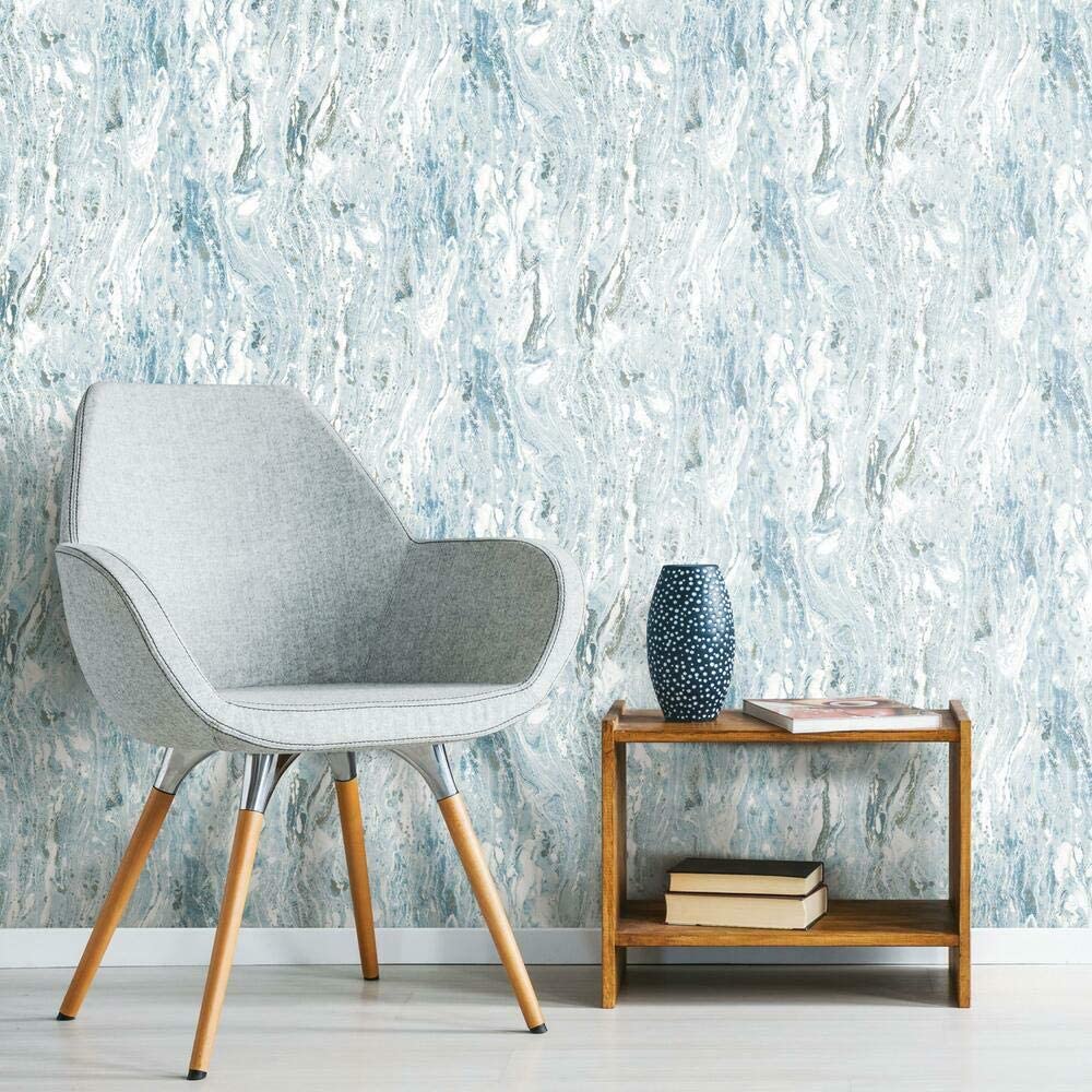 A grey upholstered armchair and a small wooden side table stand against a wall covered in blue and white marbled wallpaper.