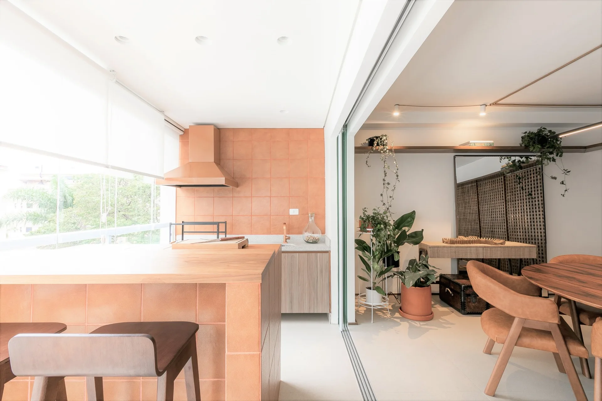 A kitchen with a terracotta tiled backsplash and island base, separated from a dining area by a sliding glass partition.