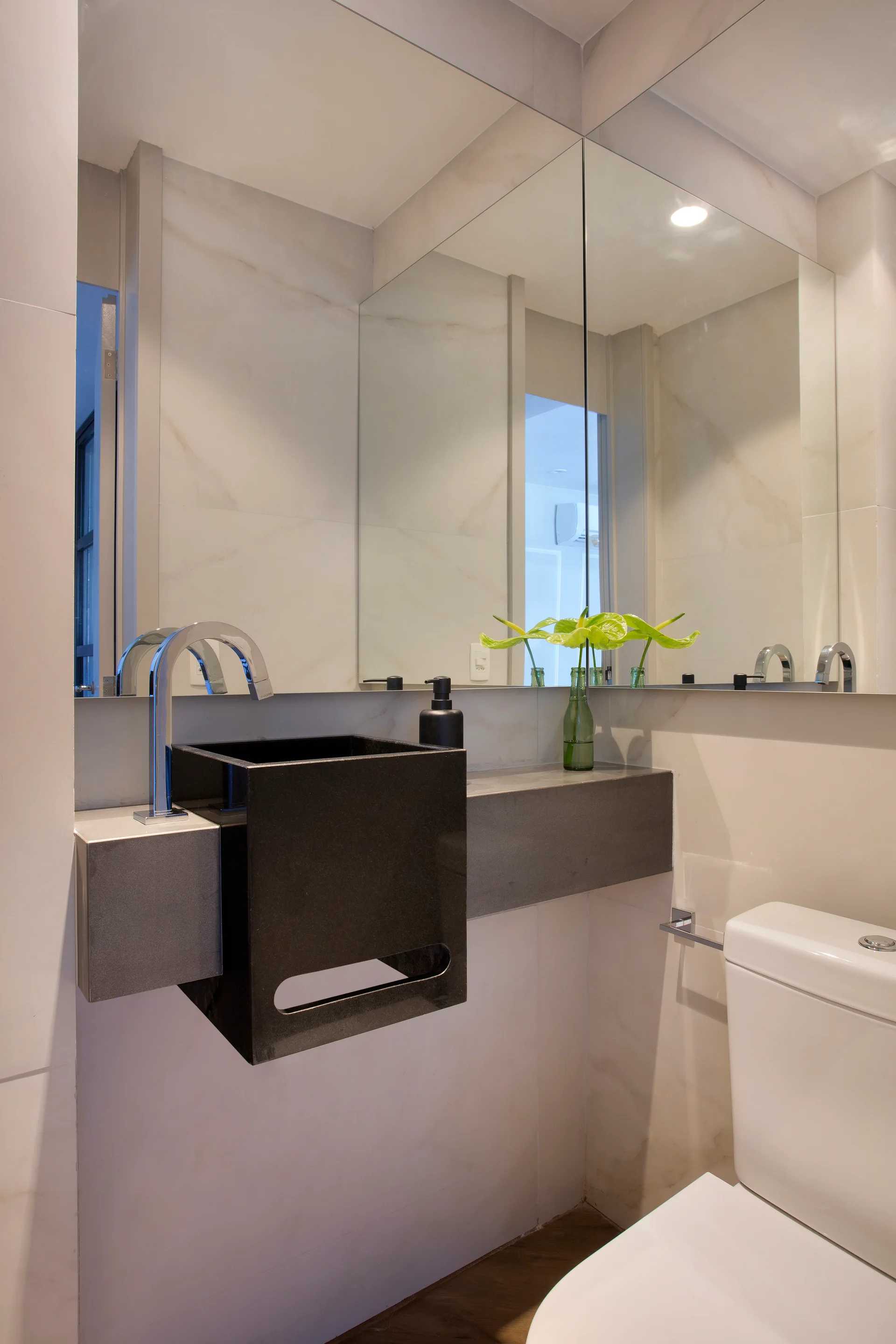 A modern powder room featuring a floating black block basin, a grey concrete ledge, and large marble-patterned wall tiles.
