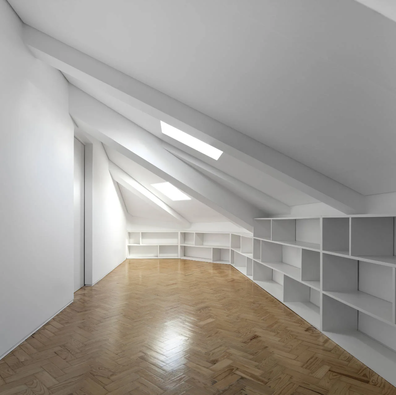 An empty minimalist attic room features a sloped white ceiling with skylights, built-in storage shelves, and a polished herringbone wood floor.