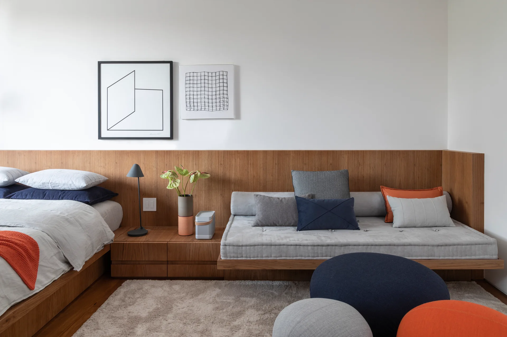 A modern bedroom with an integrated wood headboard wall, a built-in daybed, and colorful accent pillows.