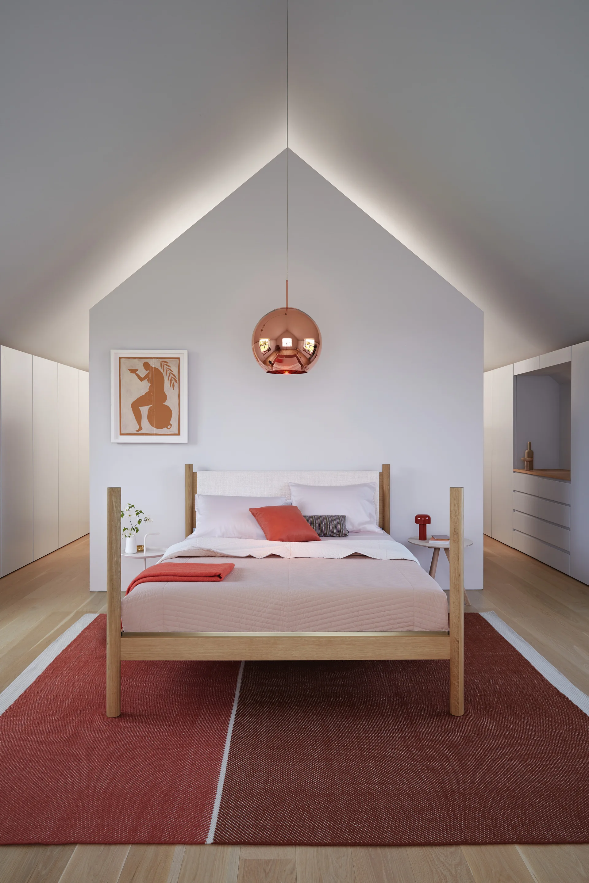 A symmetrical bedroom features a wooden bed, a copper globe pendant, and a gabled partition wall highlighted by soft overhead cove lighting.
