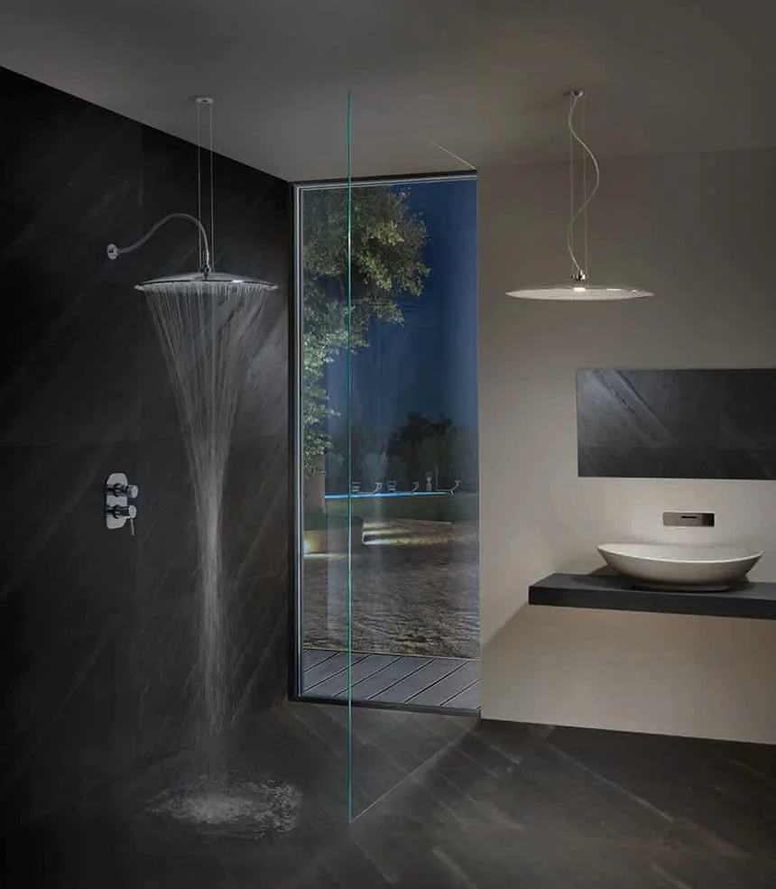 A minimalist modern bathroom features a dark charcoal stone rain shower next to a full-height glass window and a floating washbasin vanity.