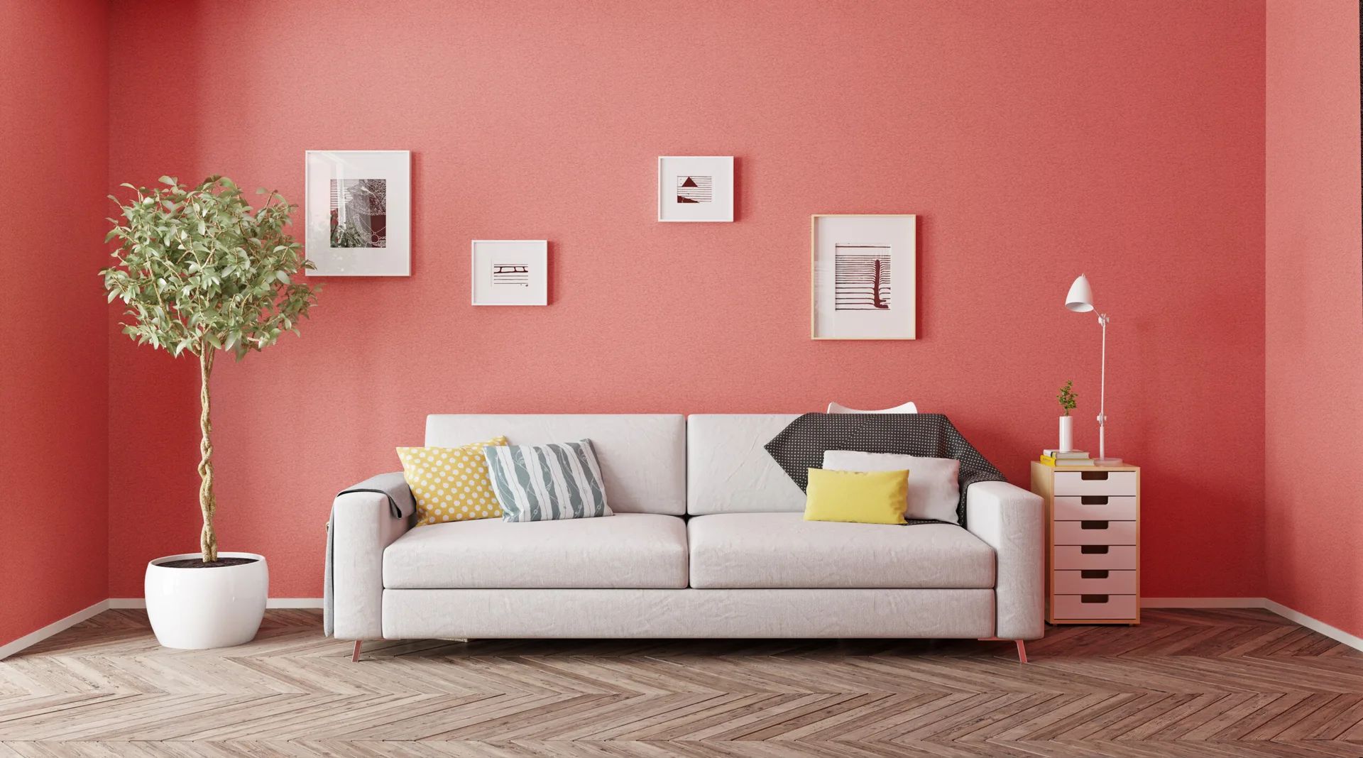 A white fabric sofa sits against a textured coral wall on a herringbone wood floor, flanked by a potted tree and a small wooden drawer unit.