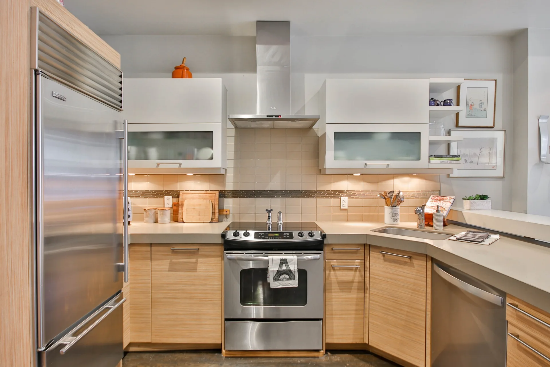 A modern kitchen features horizontal wood grain base cabinets, white upper cabinets, stainless steel appliances, and warm under-cabinet lighting.