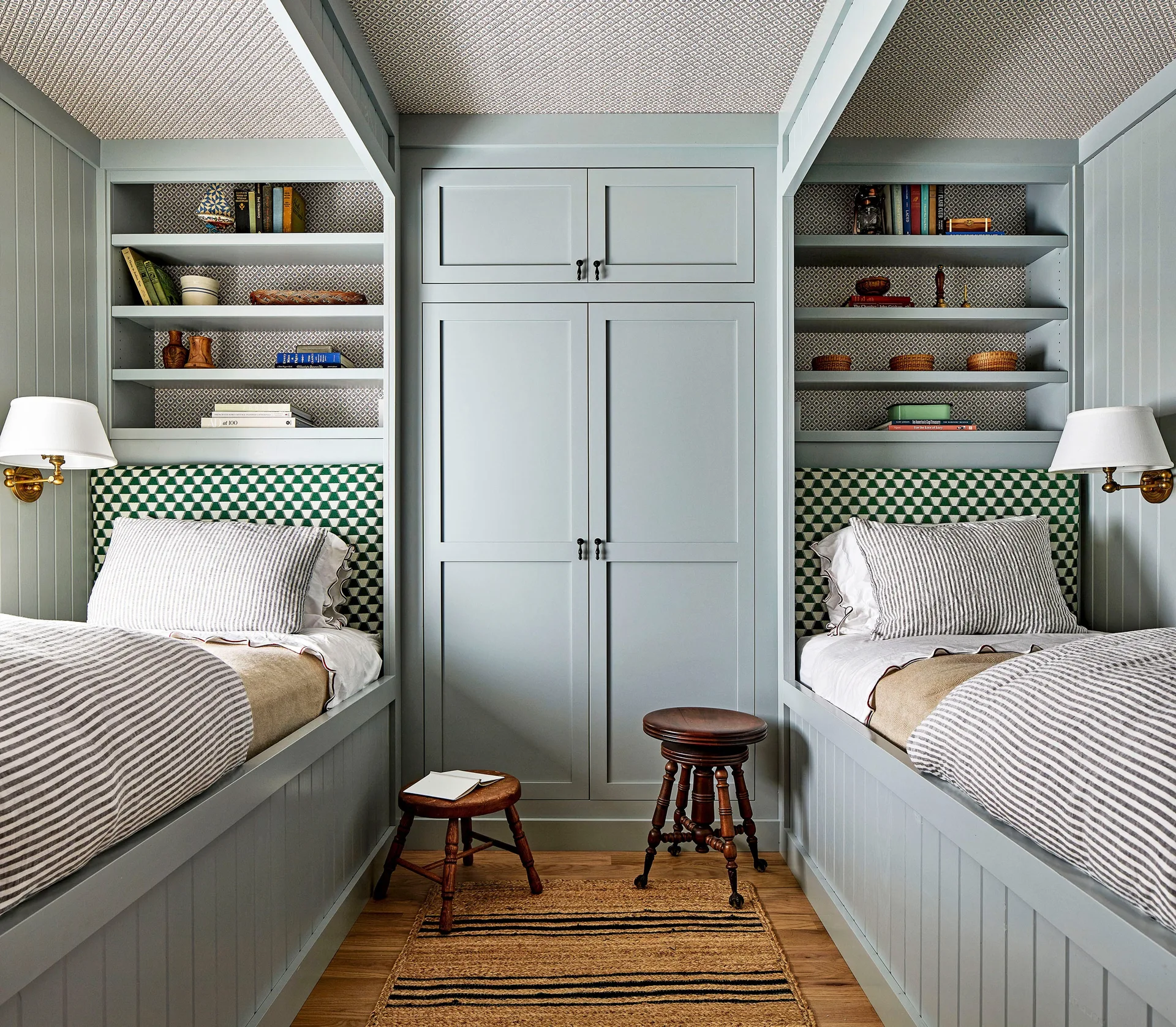 A symmetric bedroom features two built-in twin beds with striped bedding flanking a central blue wardrobe under a patterned ceiling.