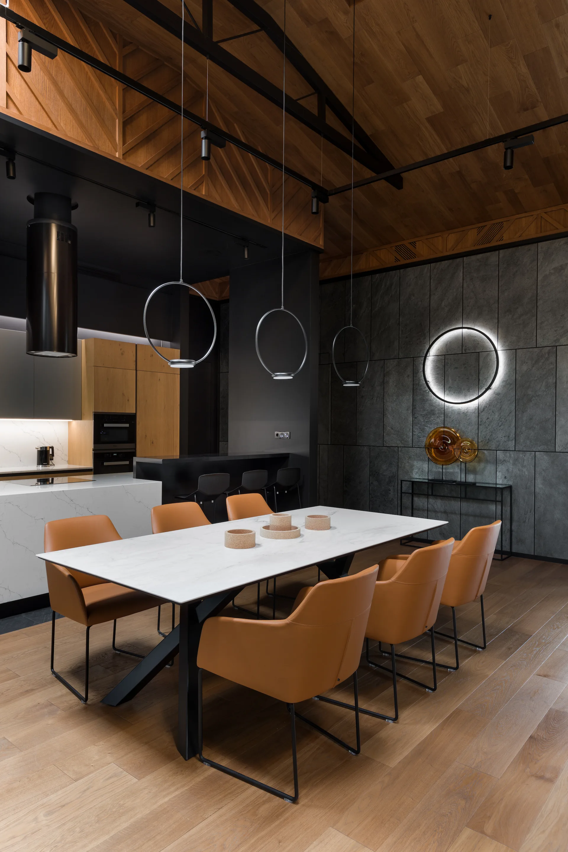 A modern dining room features a white marble table surrounded by orange leather chairs beneath a wooden plank ceiling and circular pendant lights.
