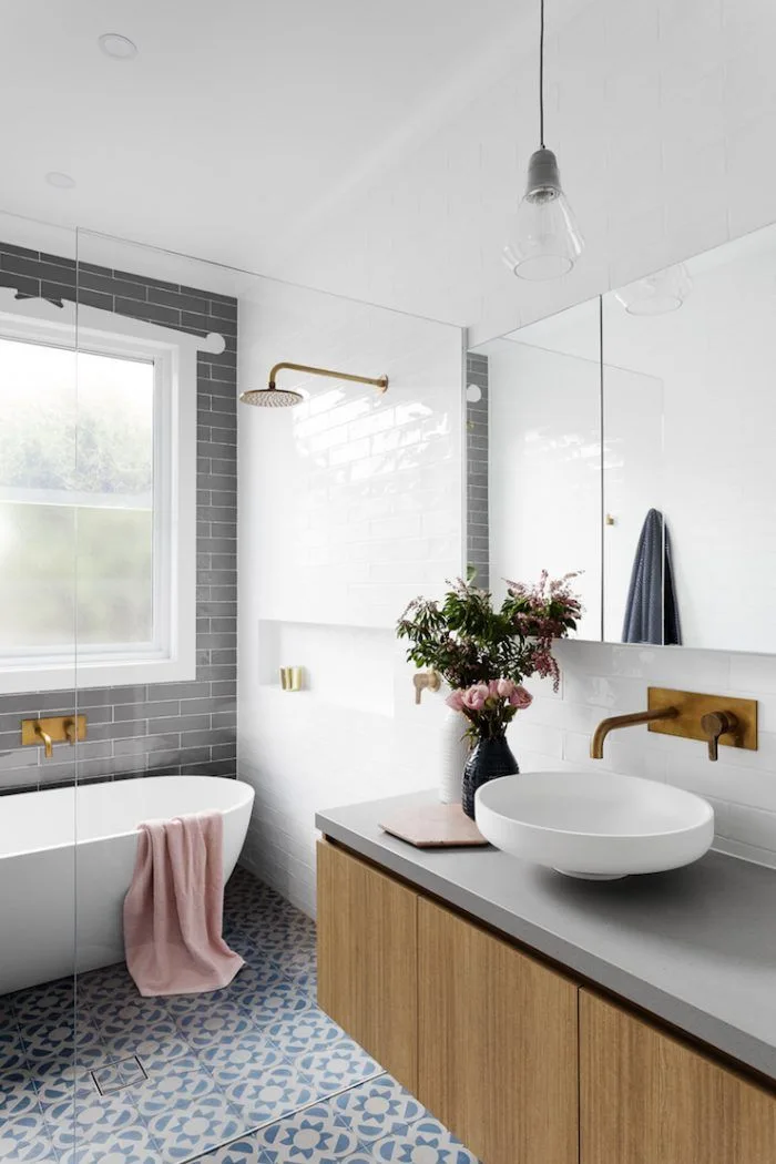A contemporary bathroom features a wood vanity with a white vessel sink, a freestanding bathtub, and a blue-and-white patterned tile floor.