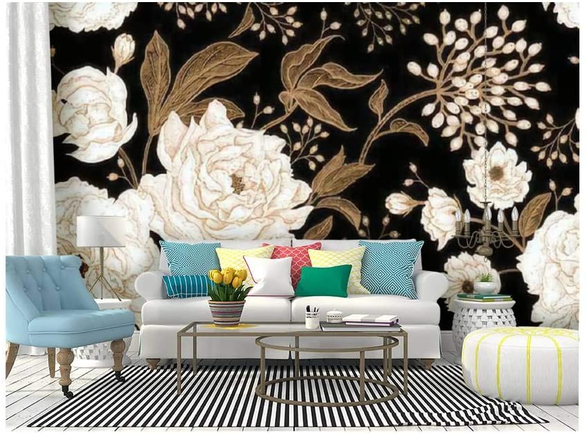 A white sofa with bright throw pillows sits before a black floral wallpaper mural on a floor covered by a black and white striped rug.