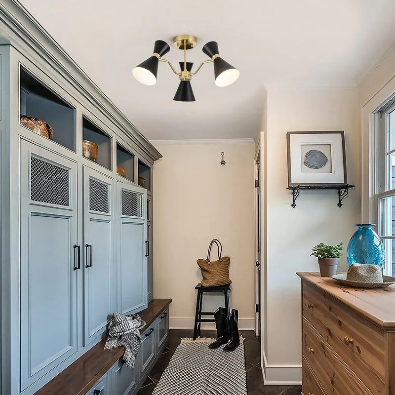 Blue built-in mudroom cabinets with a wooden bench stand across from a natural wood dresser beneath a mid-century ceiling light.