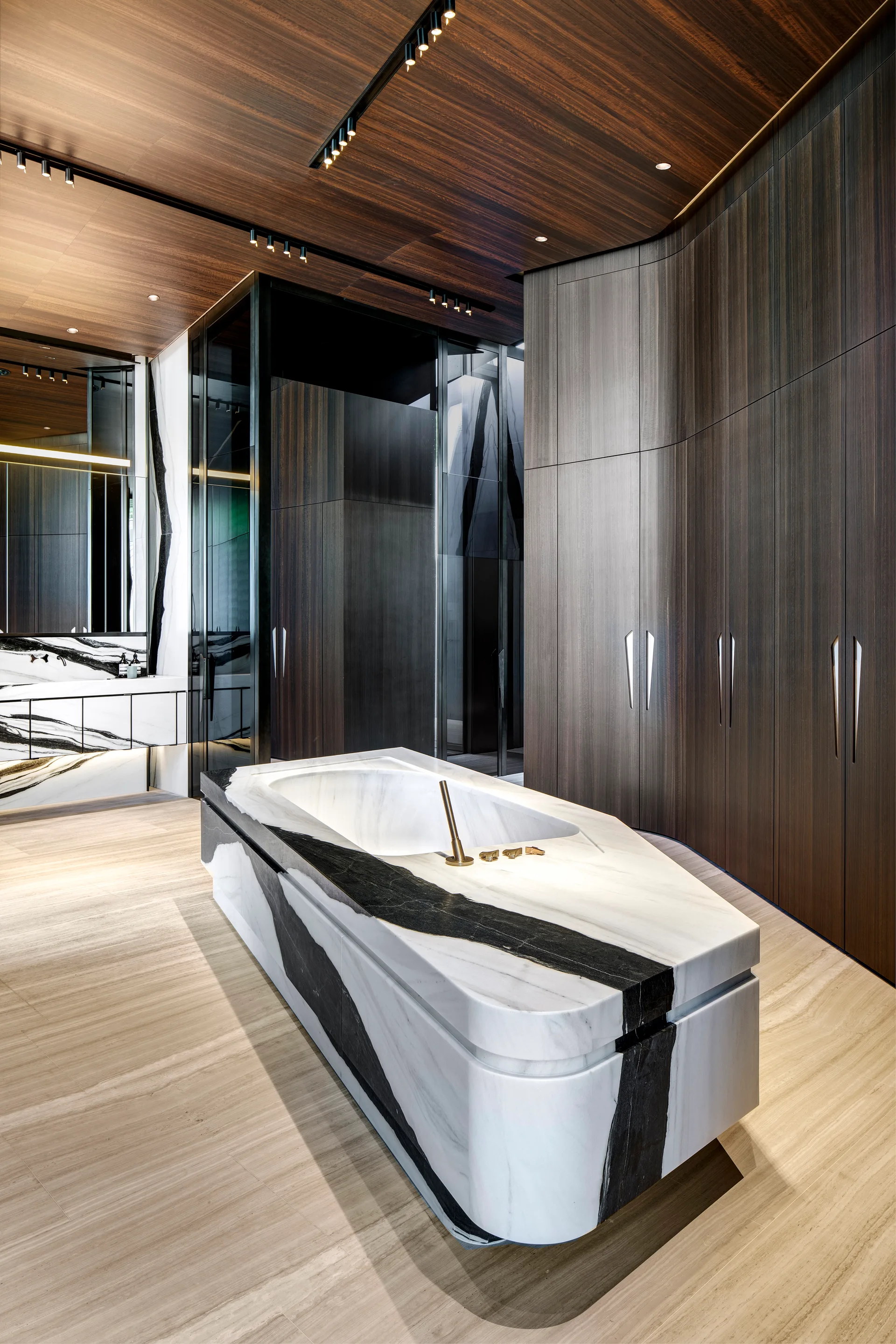A modern bathroom features a central bathtub made of black and white veined marble, surrounded by curved dark wood cabinetry and a wood plank ceiling.