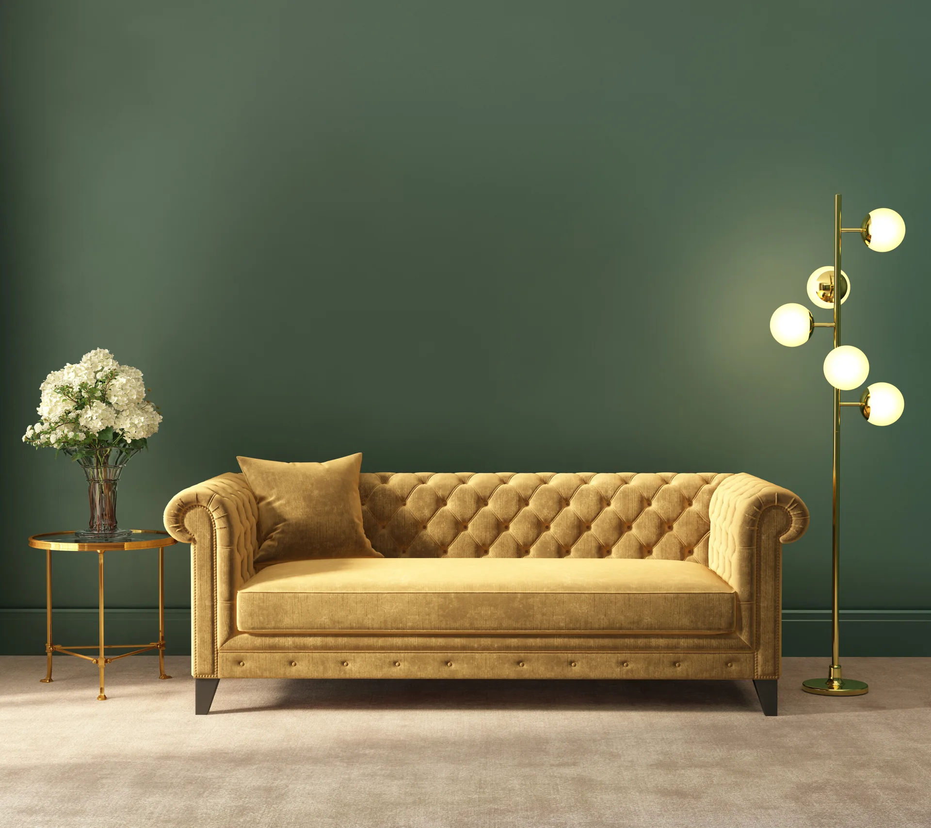 A mustard yellow velvet Chesterfield sofa stands against a deep green wall with a brass side table and a glowing globe floor lamp.