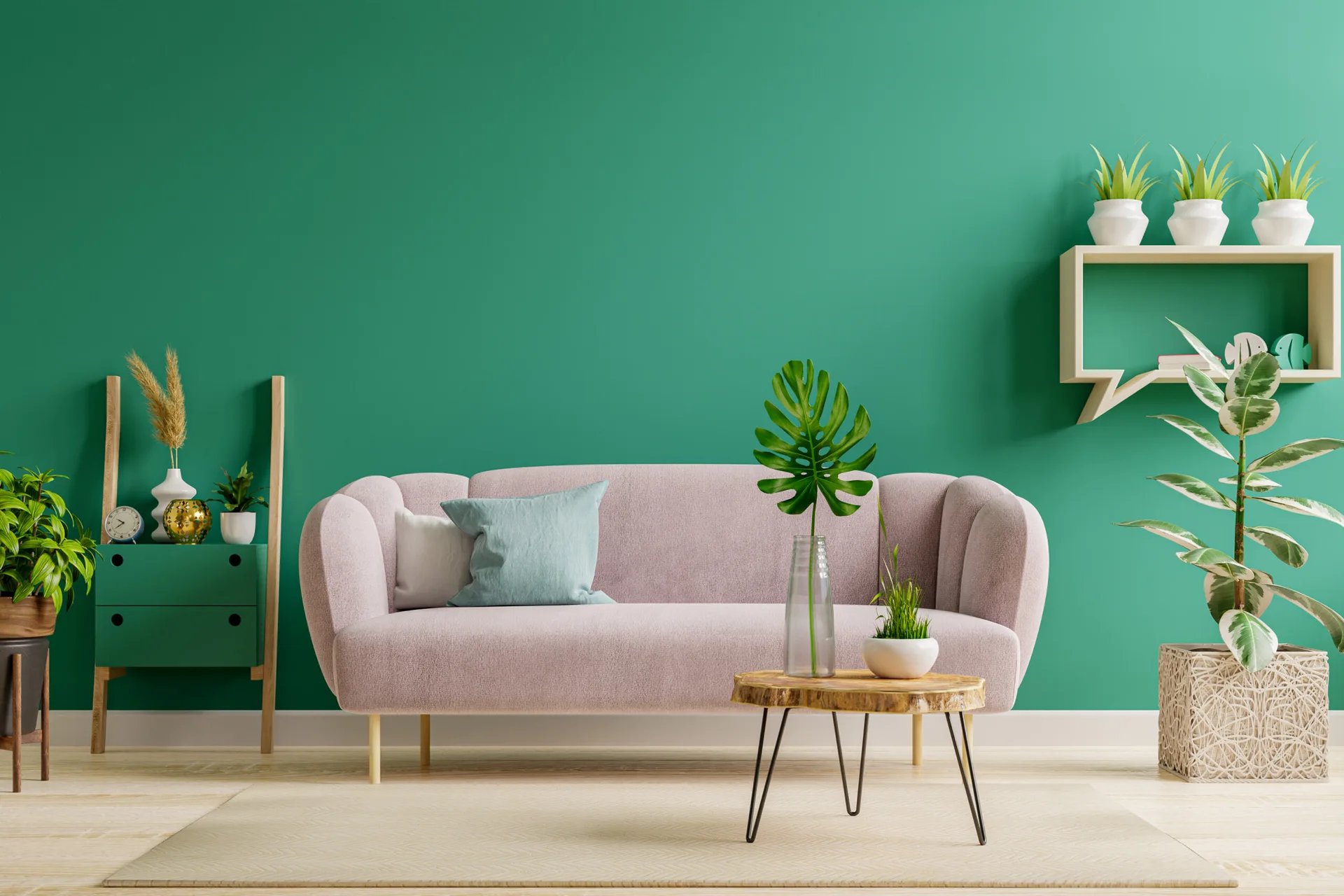 A light pink curved sofa stands against a bold green painted wall next to potted plants, a wooden accent table, and light wood shelving.