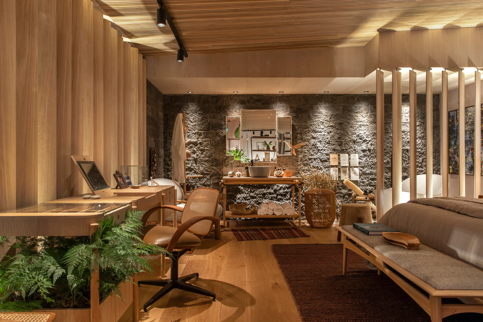 A bedroom interior featuring a wood slatted ceiling, a textured stone accent wall, a wooden vanity desk, and a matching slatted room divider.
