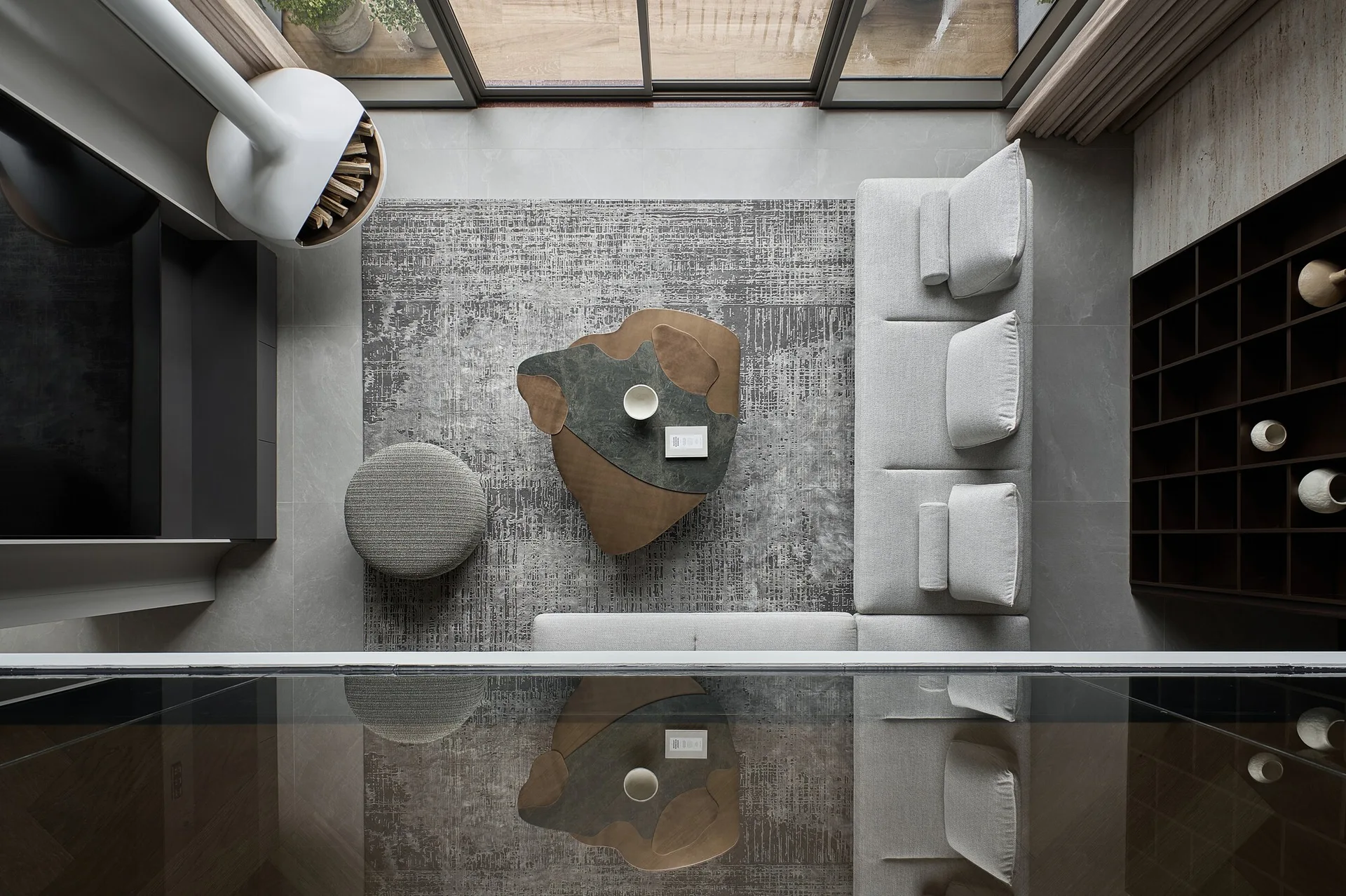 A top-down view of a contemporary living room showing a light grey modular sofa, an organic-shaped wood coffee table, and a textured area rug.