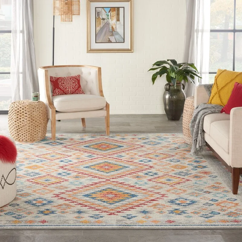 A living room featuring a large geometric patterned rug under a beige sofa and cream armchair against a white painted brick wall.