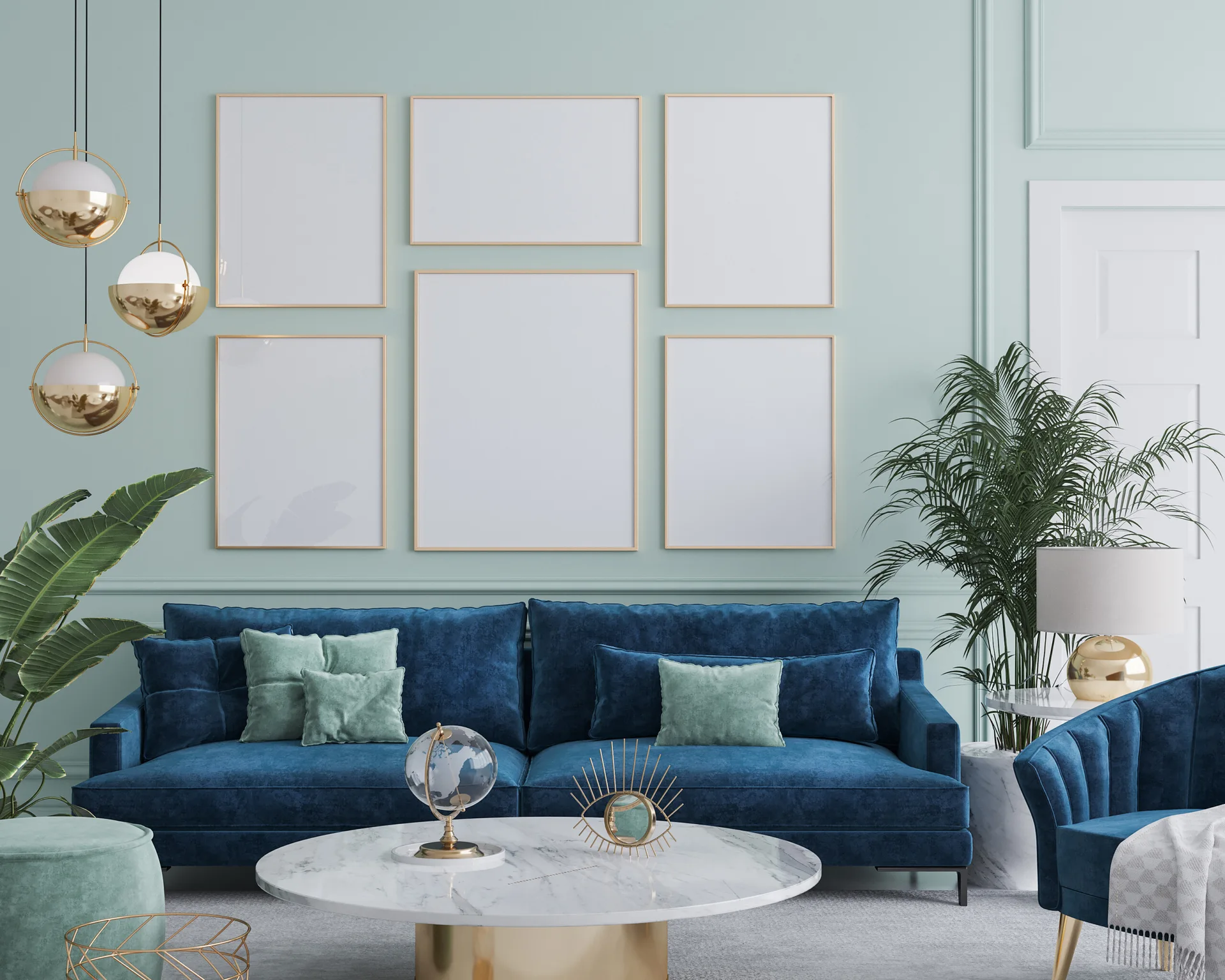 A blue velvet sofa sits against a light green paneled wall with a gallery of six gold frames, alongside a marble coffee table and gold pendant lights.