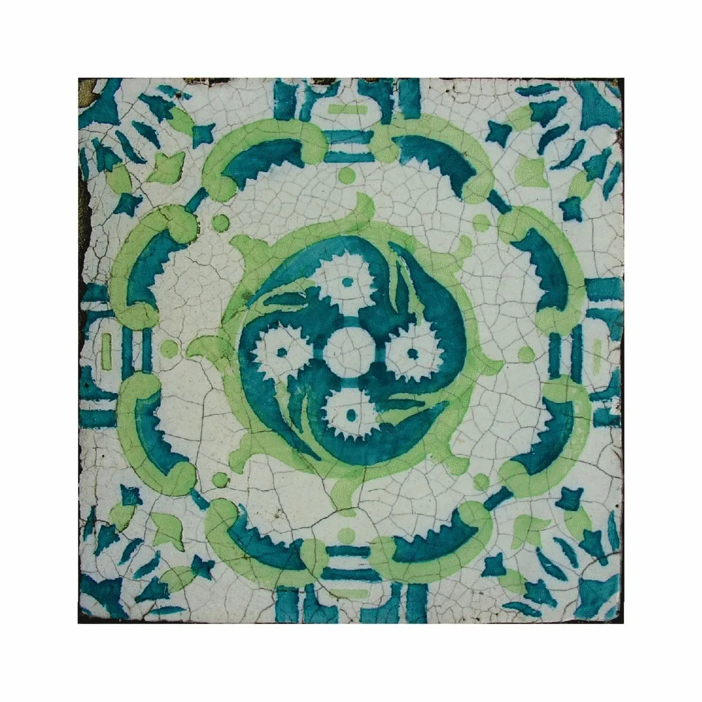 A square ceramic tile featuring a symmetrical teal and lime green floral motif on a white background with a fine crackled glaze texture.