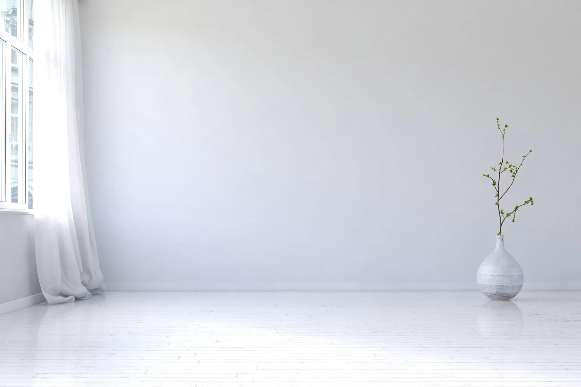 A sunlit white minimalist room features a sheer white curtain draped beside a large window and a single ceramic floor vase with a green stem.