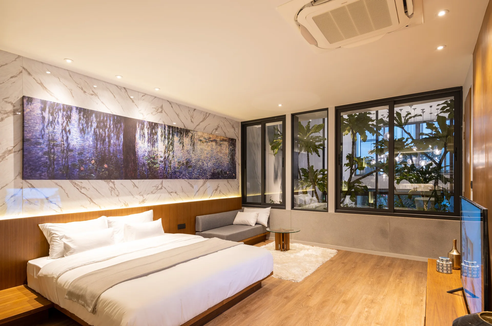 A modern bedroom features a platform bed, a large panoramic painting above a wood and marble headboard, and windows looking out to a courtyard.