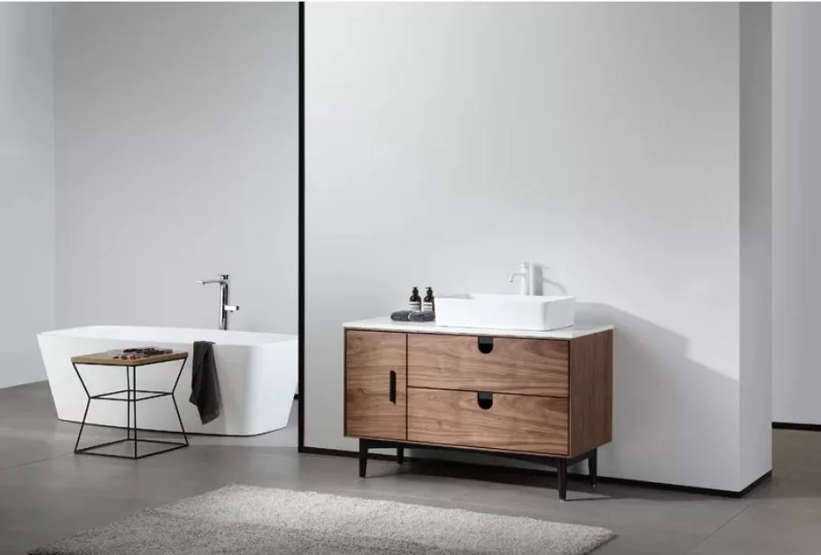 A modern minimalist bathroom featuring a walnut wood vanity with a white vessel sink, a white partition wall, and a freestanding bathtub.
