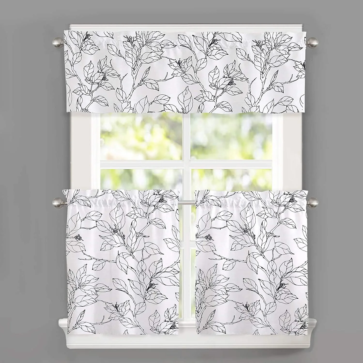 White curtains with a black botanical line art print hang from metal rods on a window surrounded by a grey wall.