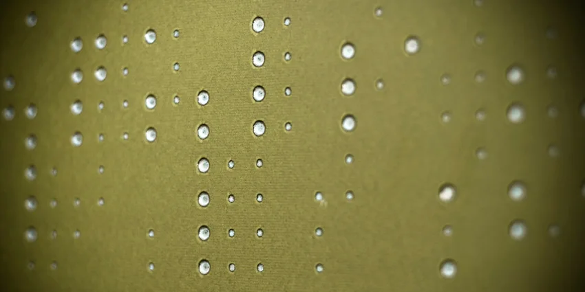 An extreme close-up of an olive green acoustic wall panel featuring a matte texture and a pattern of circular perforations in varying sizes.