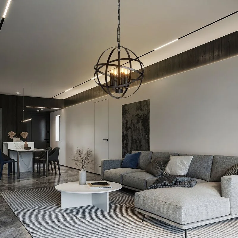 A modern living room features a grey sectional sofa, a round white coffee table on a striped rug, and a large black orb chandelier hanging from the ceiling.