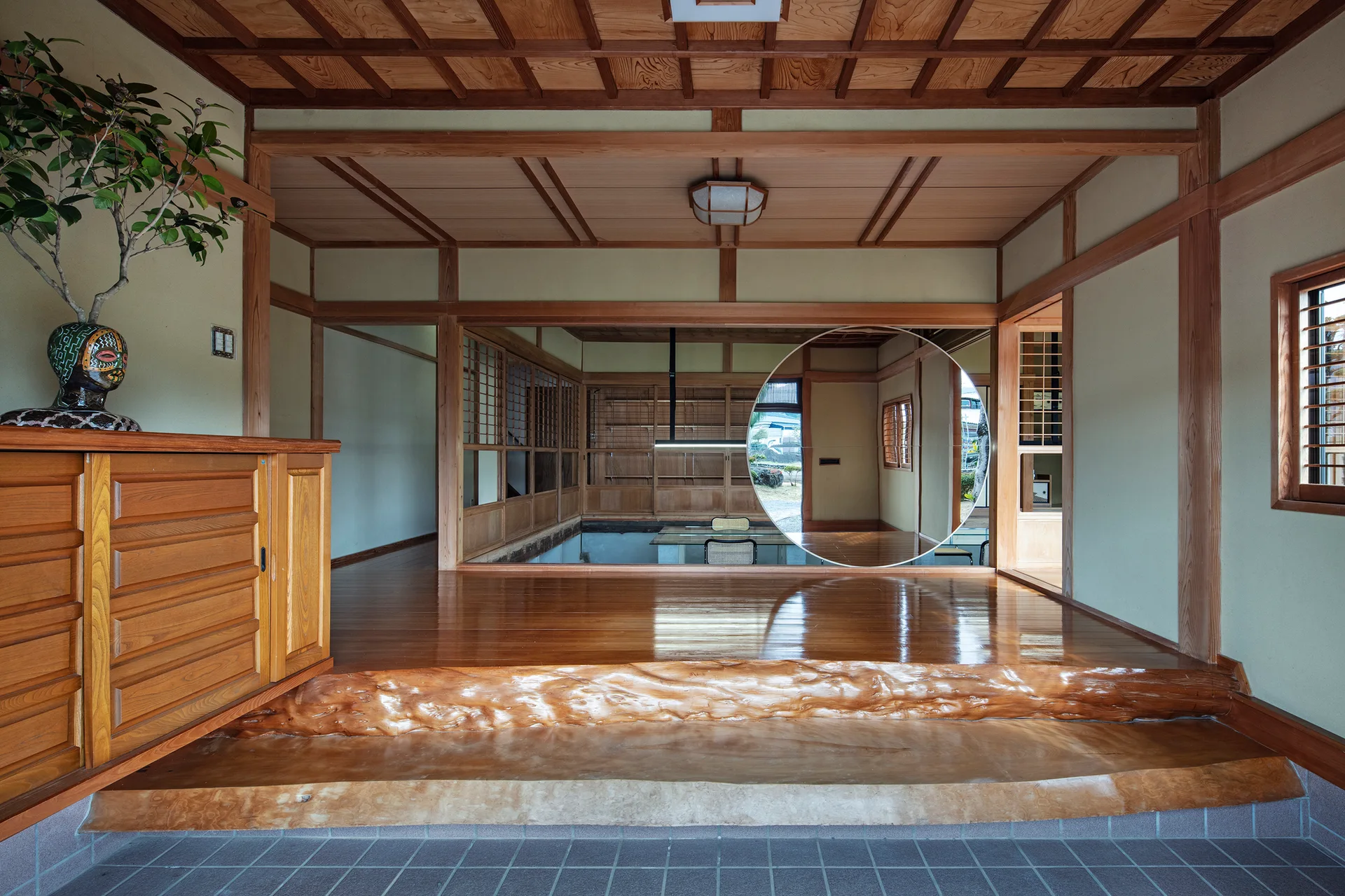 A traditional Japanese entryway with a polished wood raised platform, a rustic natural log step, and a grid pattern ceiling.