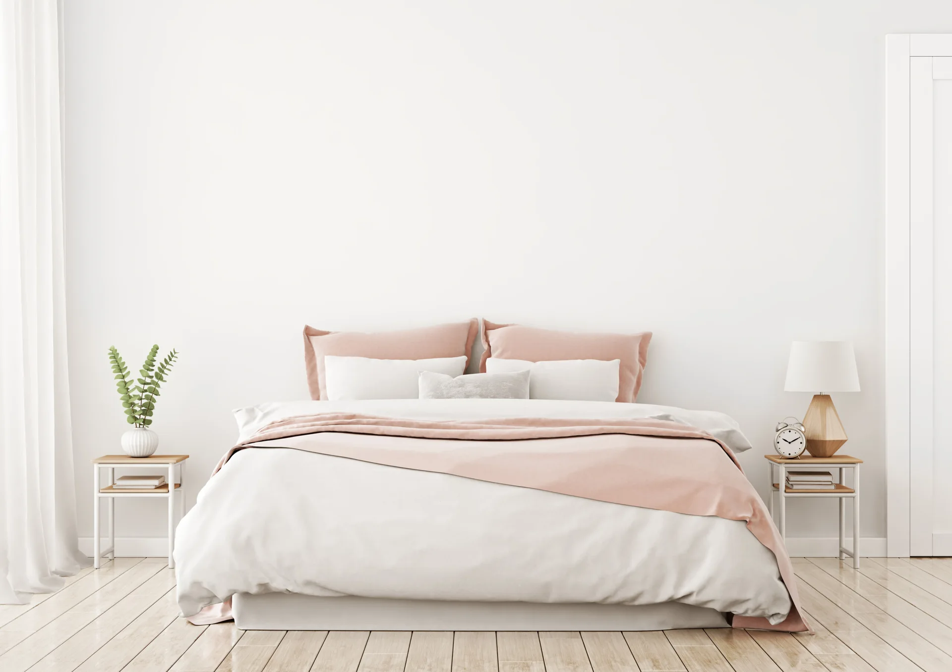 A minimalist bedroom features a bed with blush pink and white bedding, flanked by two matching wood and metal nightstands on a light wood floor.