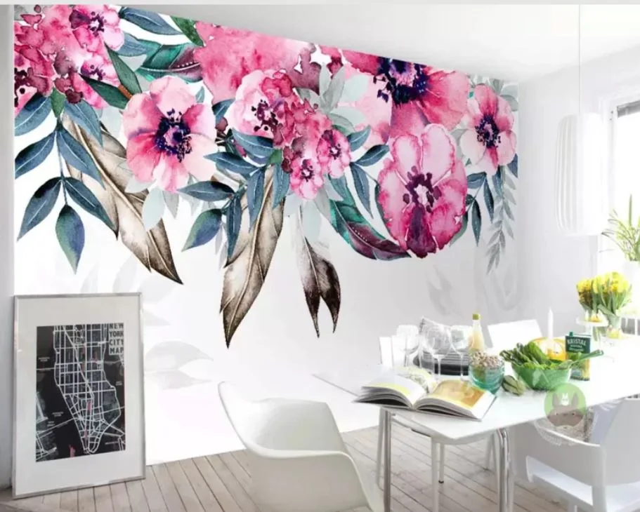 A modern white dining table and chairs set against a large pink and green watercolor floral mural wall in a bright room.