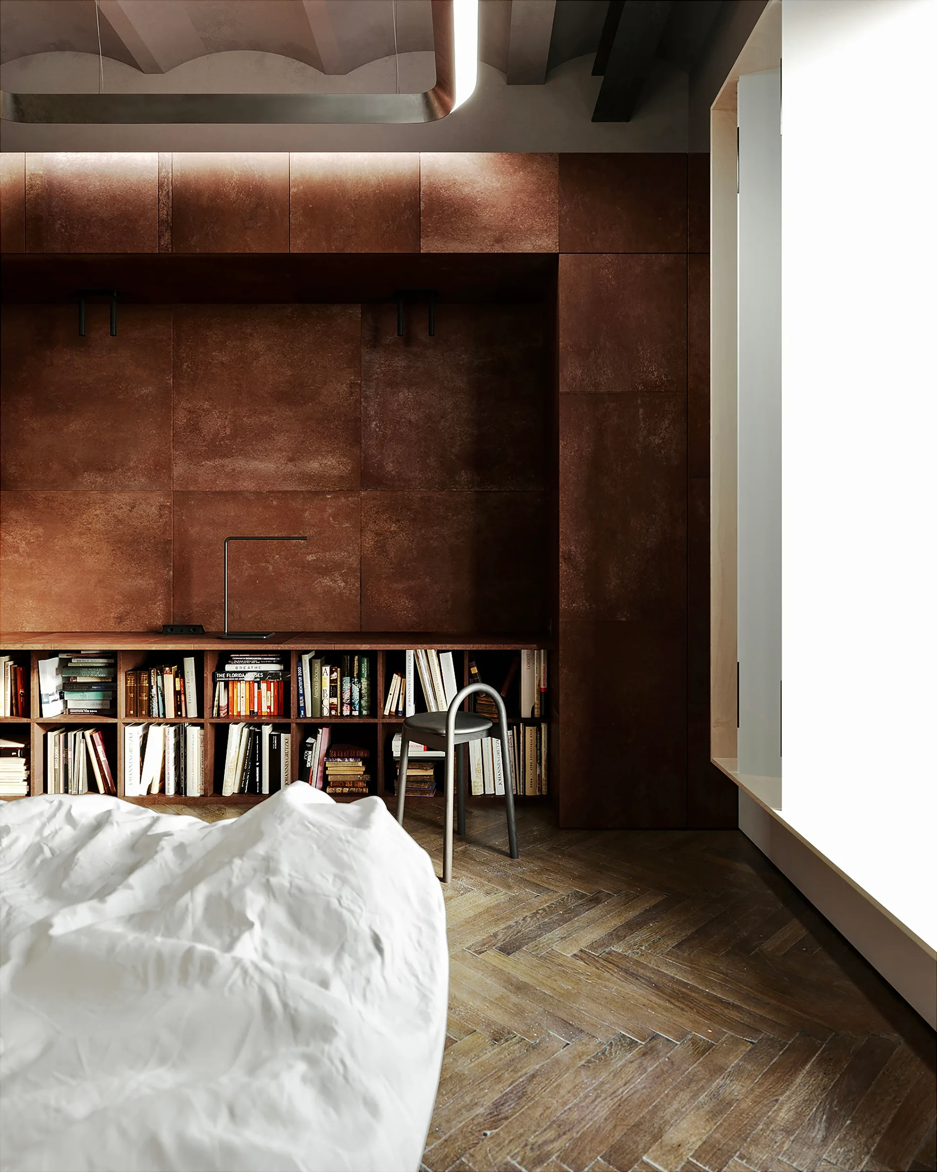 A modern bedroom features a white bed, a low integrated wood bookshelf filled with books, rust-colored textured wall panels, and a herringbone floor.