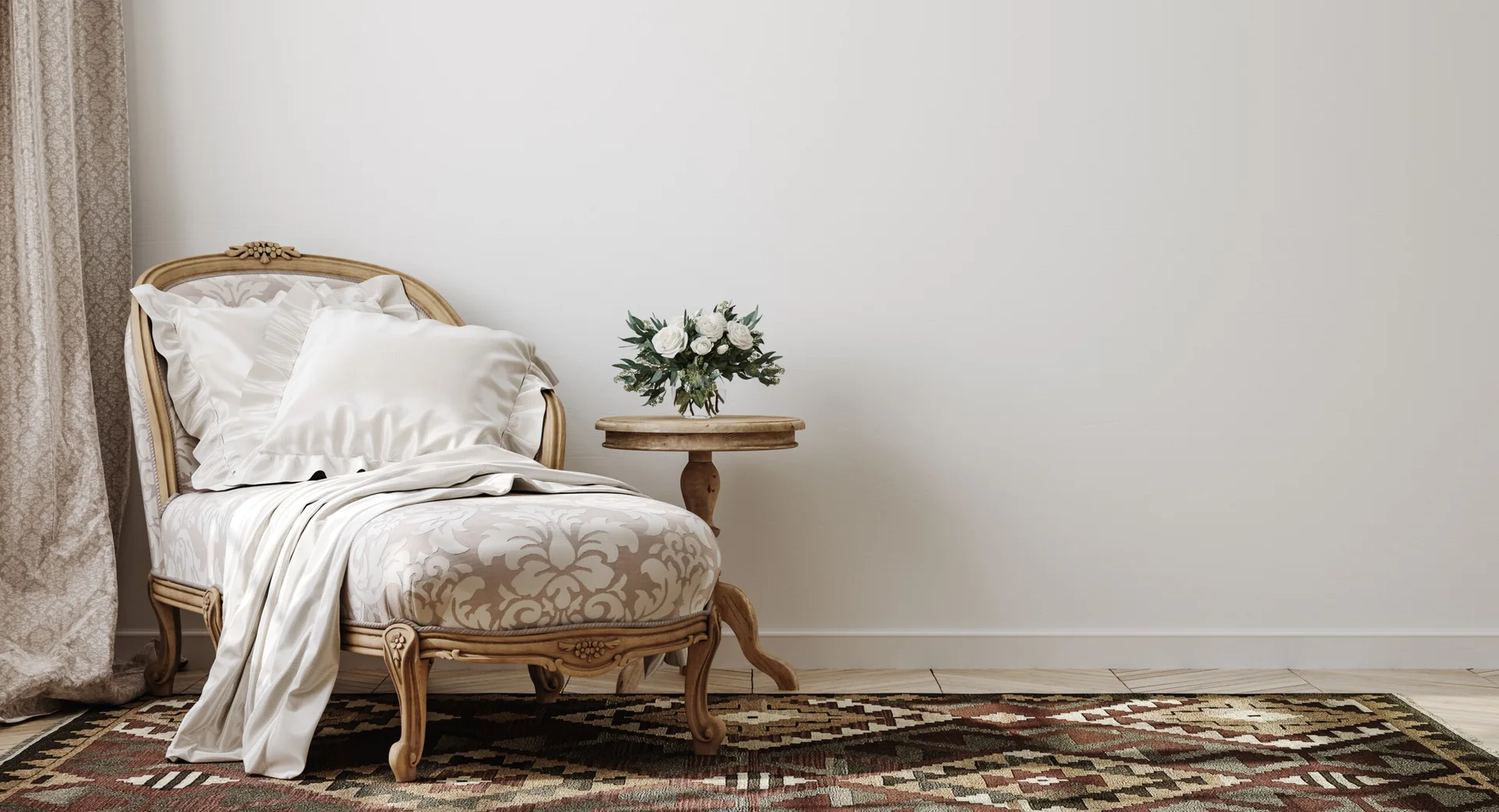 A French country chaise longue with damask upholstery sits next to a small wooden pedestal table on a patterned rug against a plain white wall.