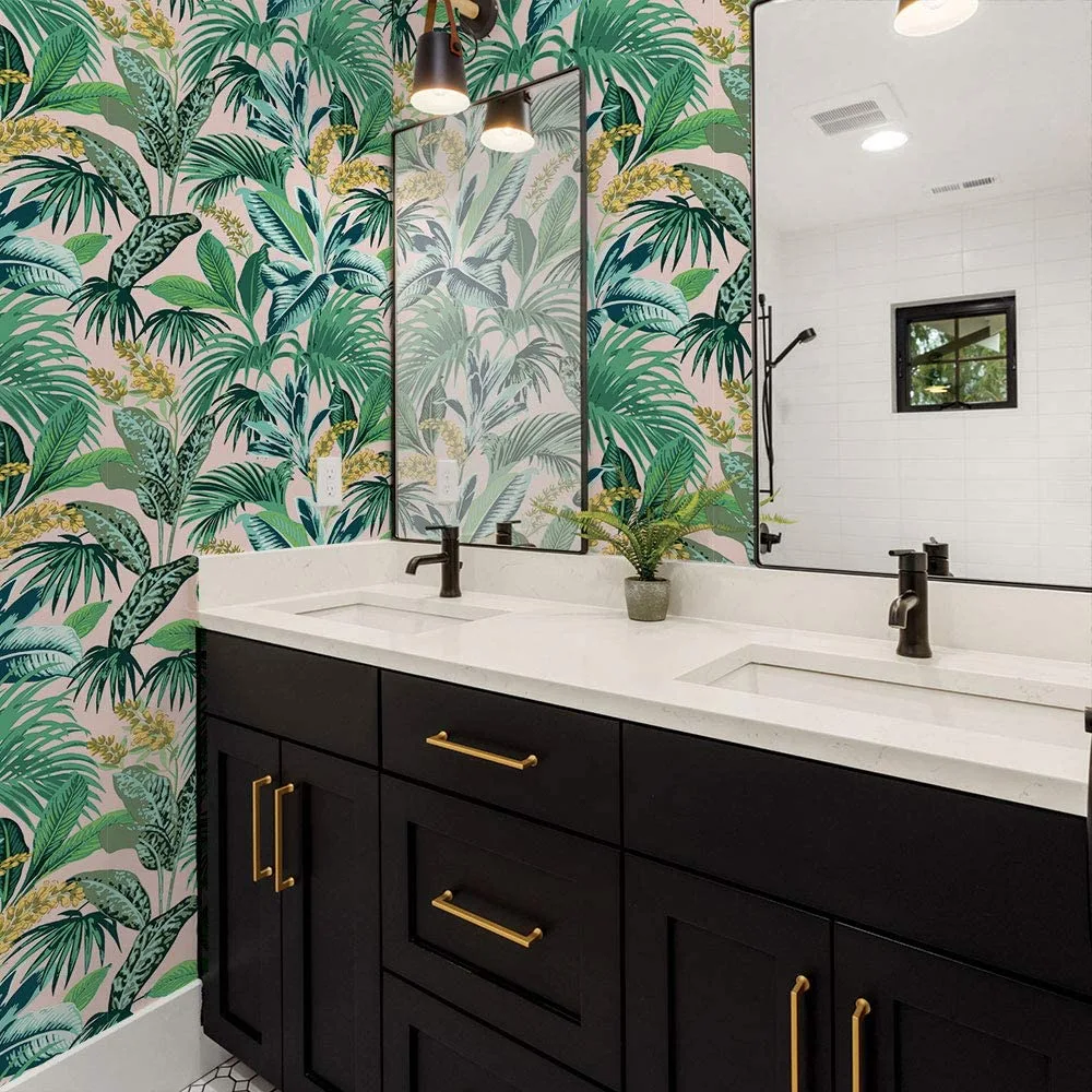A modern bathroom features a black double vanity with gold handles set against a pink and green botanical wallpaper and matching mirrors.