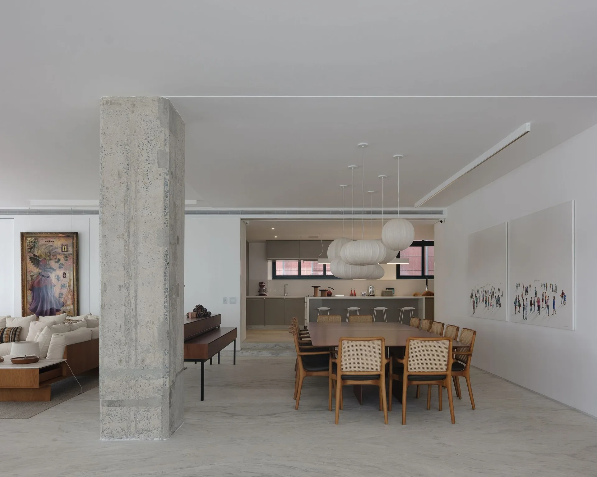 An open-concept dining area features a large wood table with cane-back chairs, a raw concrete pillar, and clustered white paper pendant lights.