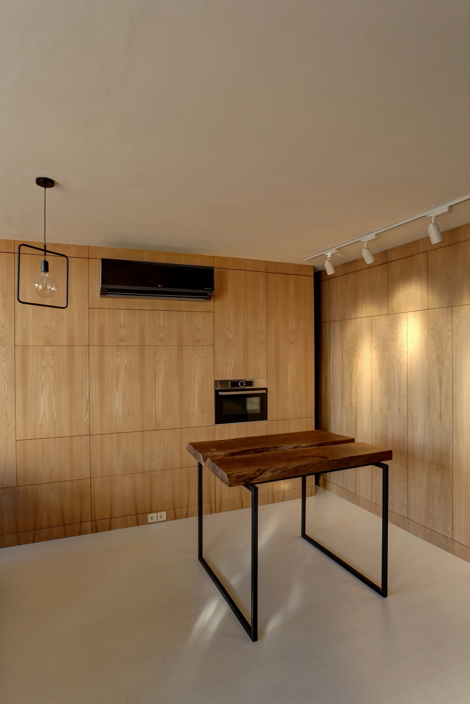 A modern kitchen featuring a live-edge wood island table and floor-to-ceiling wood paneling with an integrated oven.