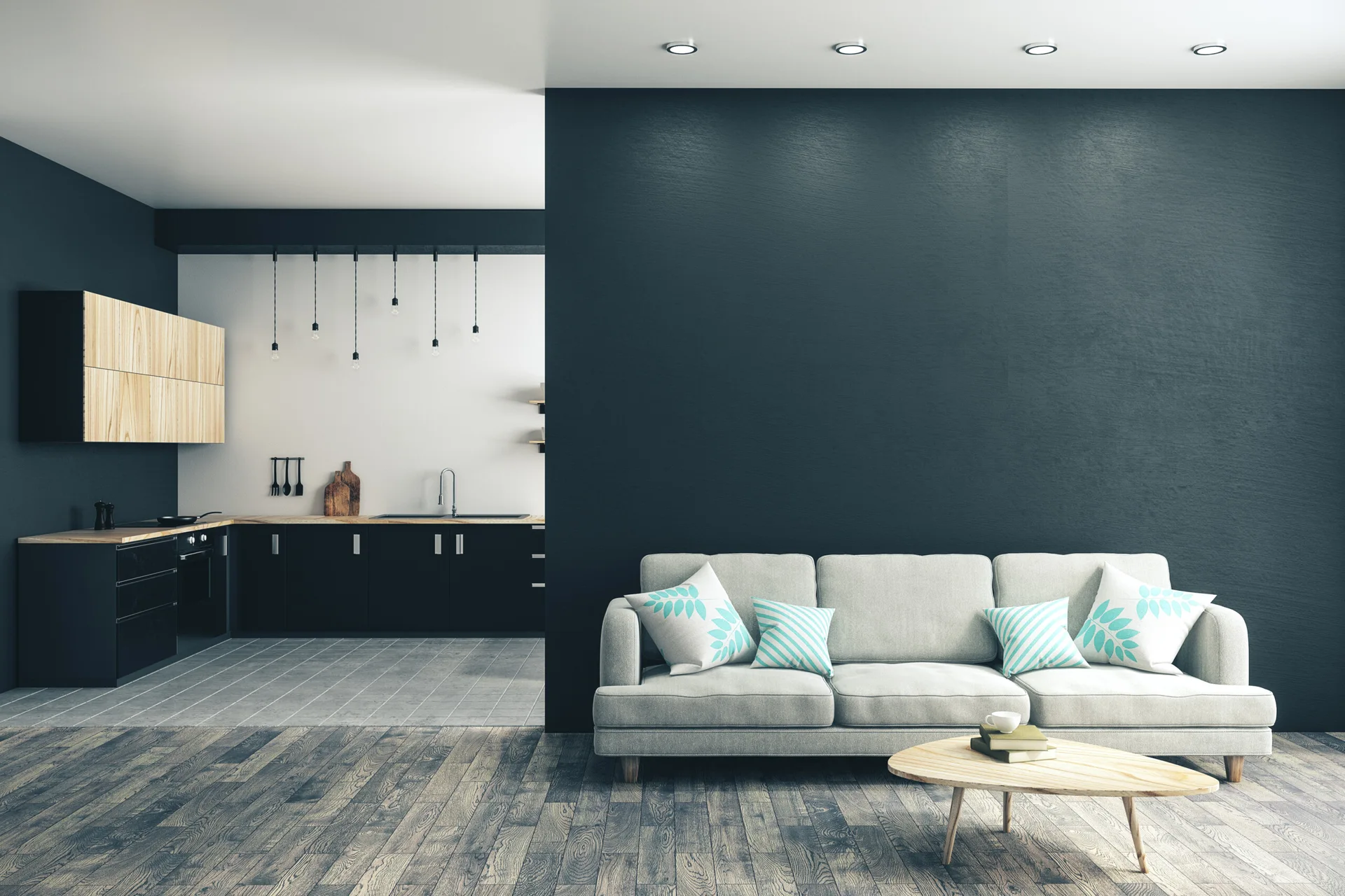 A light grey sofa sits against a dark charcoal accent wall next to an open kitchen with black and wood cabinets.