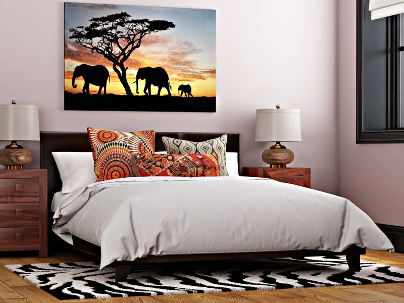 A bedroom with soft pink walls features a bed with patterned pillows, dark wood nightstands, and a black-and-white zebra print rug.