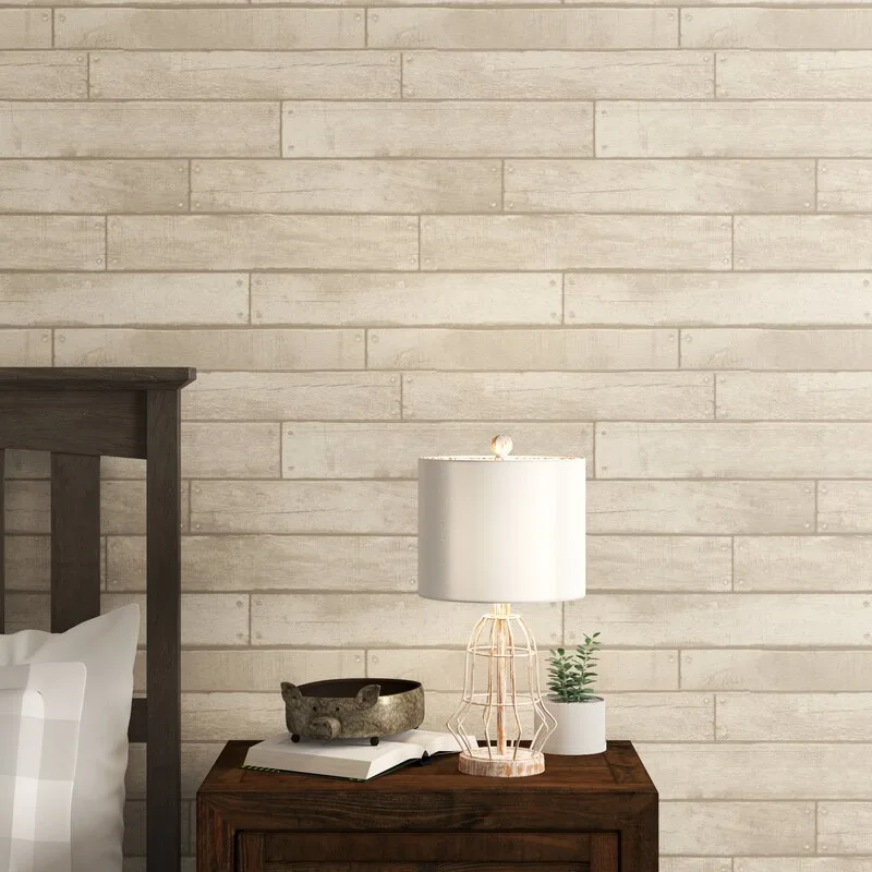 A dark wood nightstand with a wire-cage lamp and decorative accessories stands against a wall with beige wood plank wallpaper.