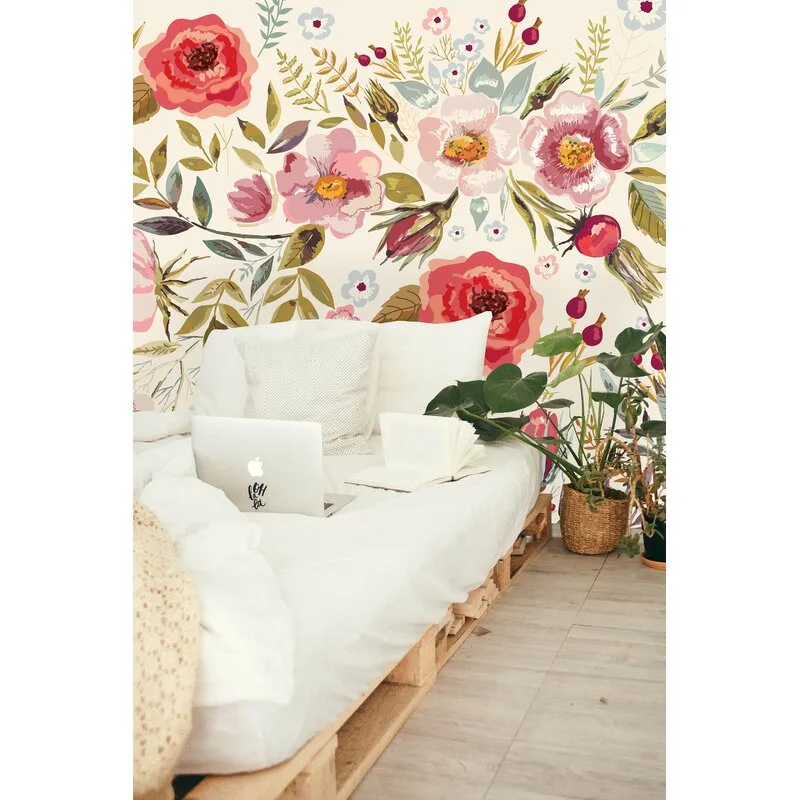 A low wooden pallet bed with white bedding is positioned against a wall featuring large-scale pink and red watercolor floral wallpaper.