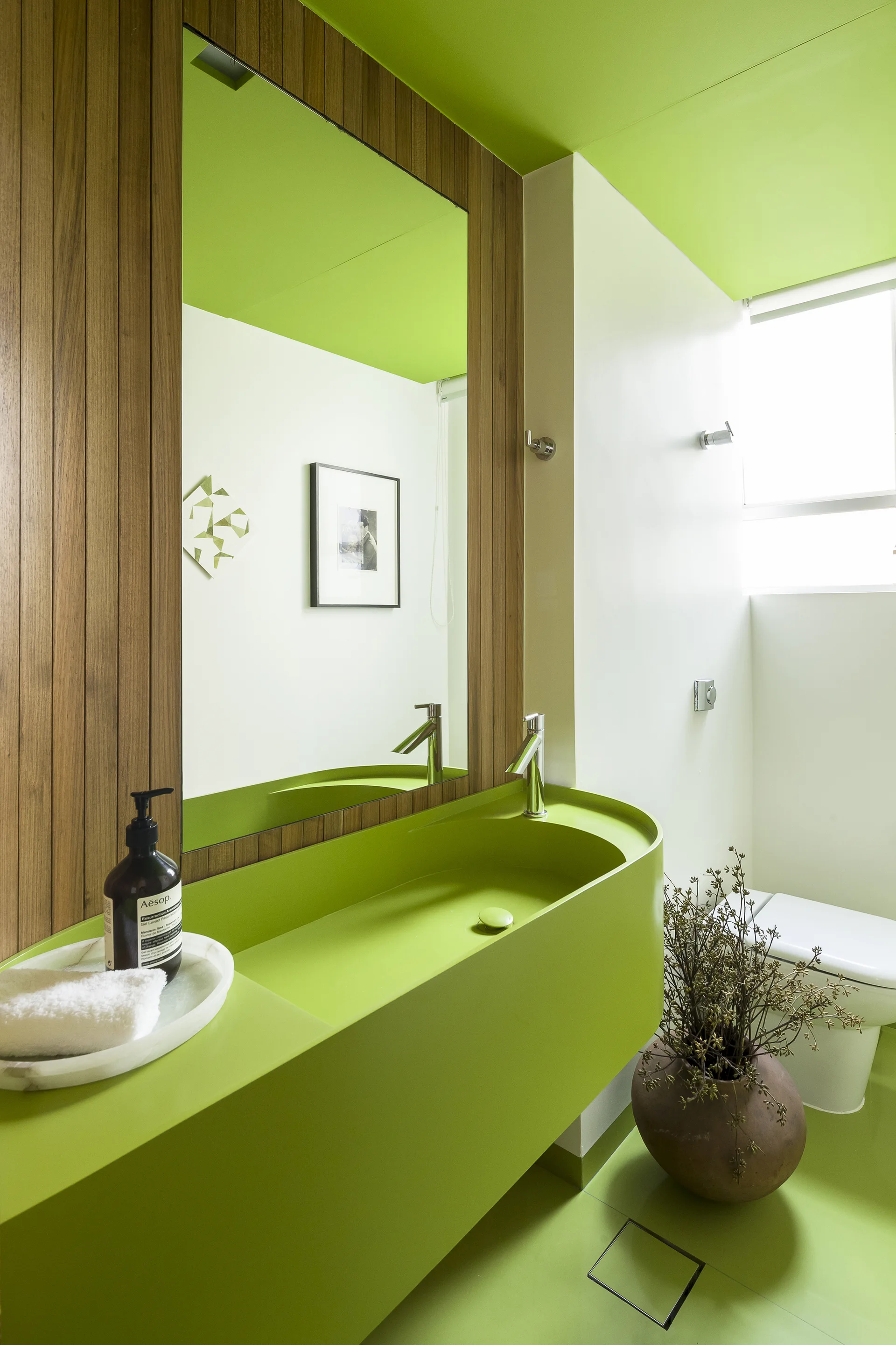 A modern bathroom featuring a lime green integrated sink vanity, matching painted ceiling and floor, and a vertical wood slat accent wall.