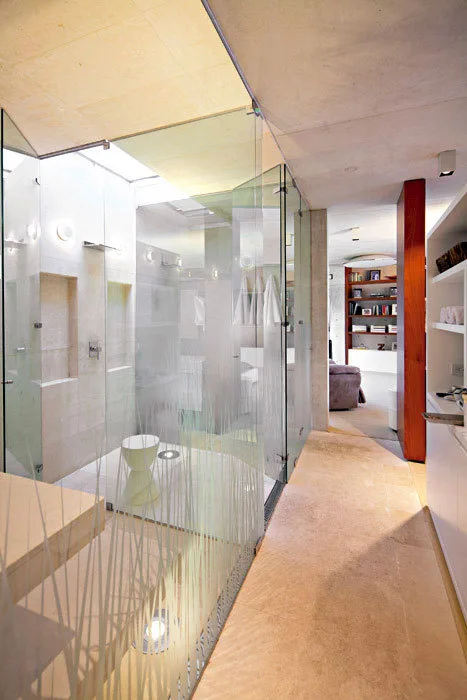 A modern bathroom featuring a glass-enclosed walk-in shower with a frosted grass pattern on the lower panels and beige stone flooring.