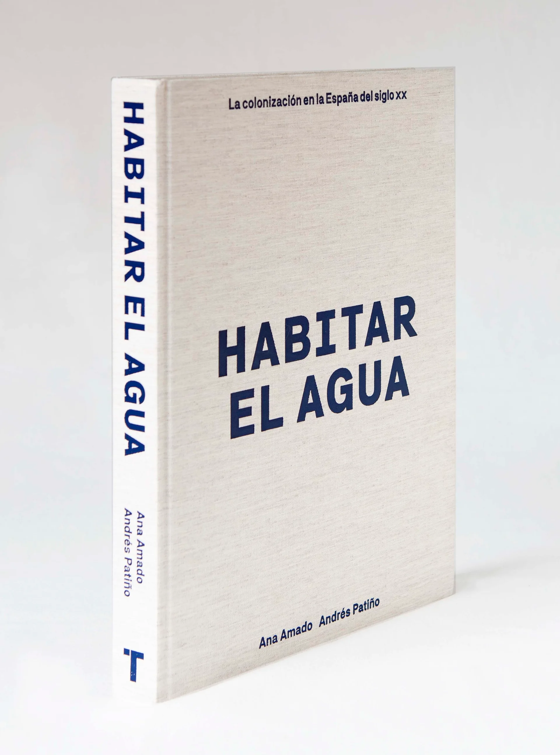 A textured beige hardcover book with blue lettering on its spine and cover stands upright against a white background.
