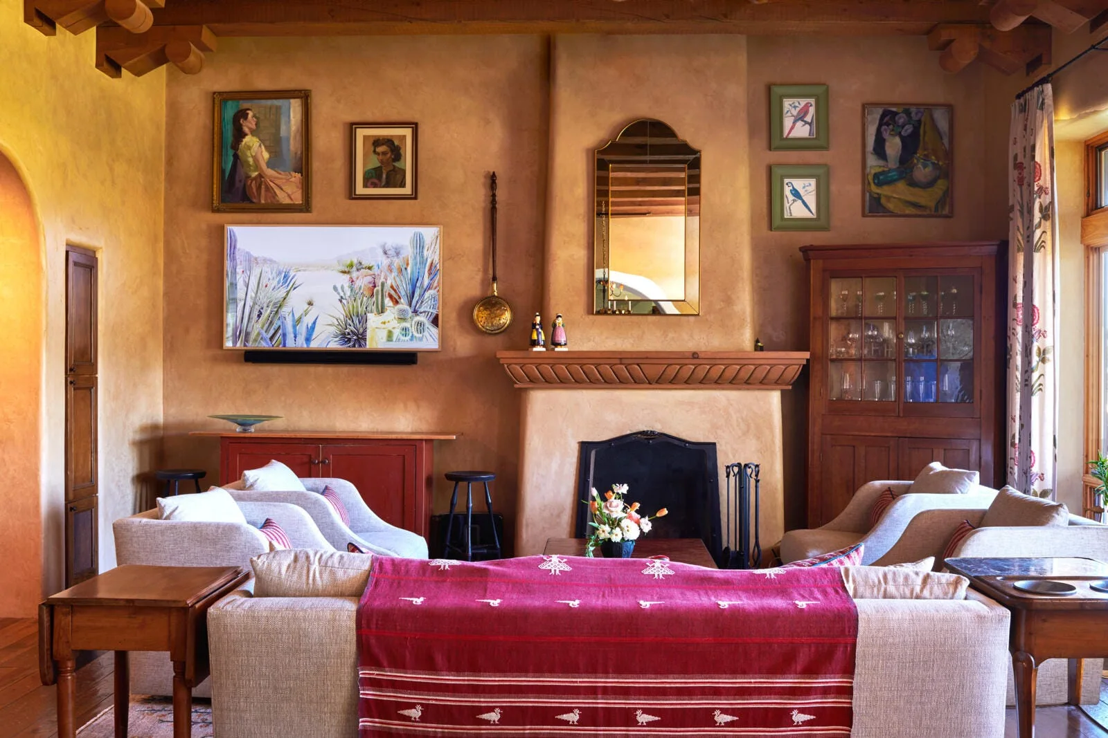 A Southwestern living room featuring textured terracotta plaster walls, a fireplace, exposed wood ceiling beams, and beige upholstered sofas.