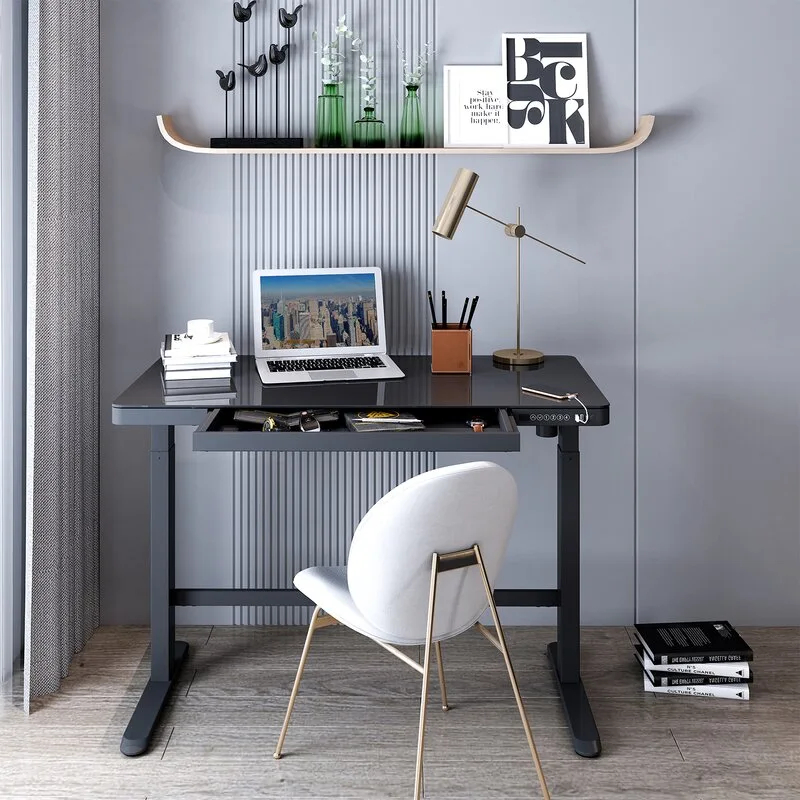 A contemporary home office setup features a black glass-top desk and white upholstered chair against a grey slatted accent wall.